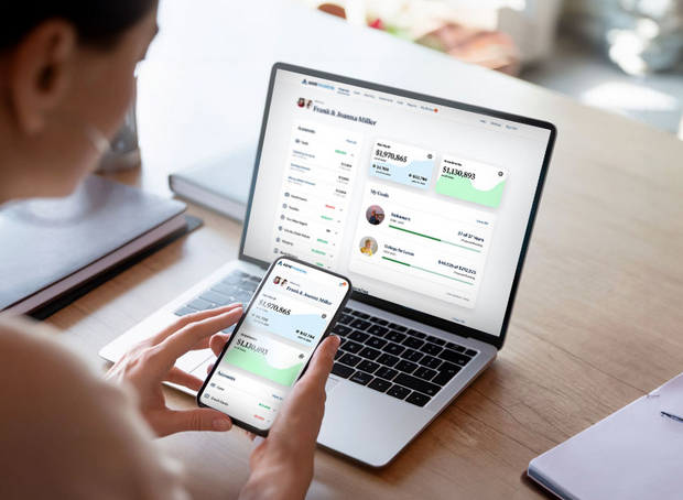 Client reviewing the eMoney mobile app on her phone alongside the desktop dashboard